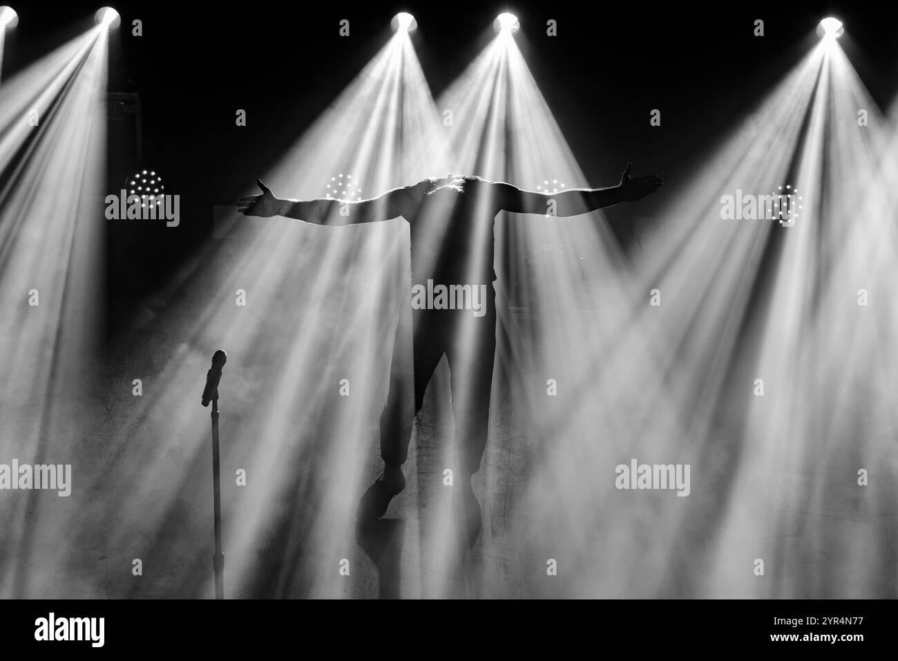 Egor Shkutko (vocals) entering the stage while spreading his arms like an eagle, against a backdrop of light beams, while on stage with Molchat Doma, live on stage on 9th November 2024 at Fållan for the Stockholm, Sweden date of their Belaya Polosa tour (B&W version) Stock Photo