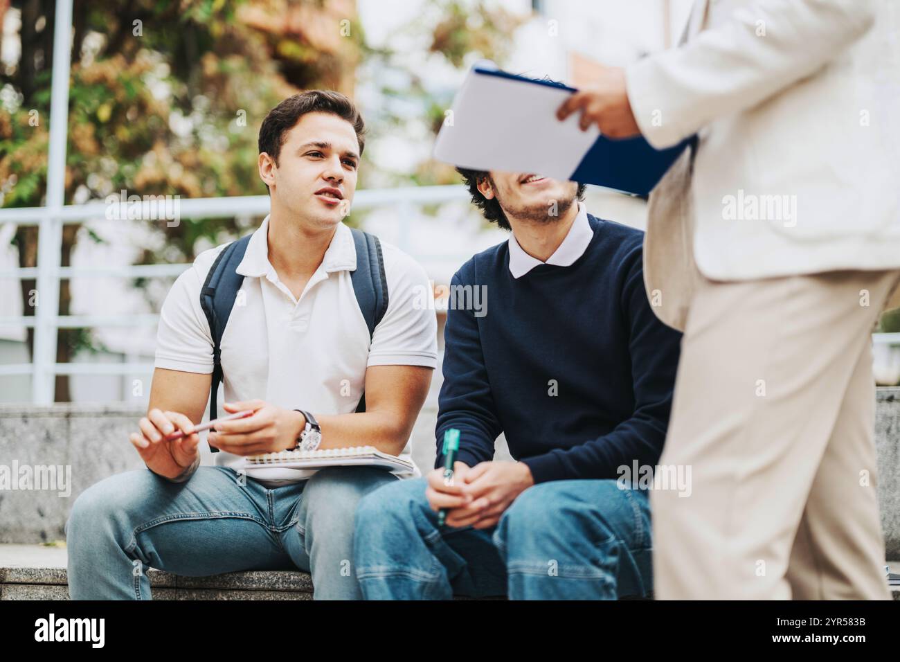 Students collaborating with professor outdoors on a sunny day Stock Photo