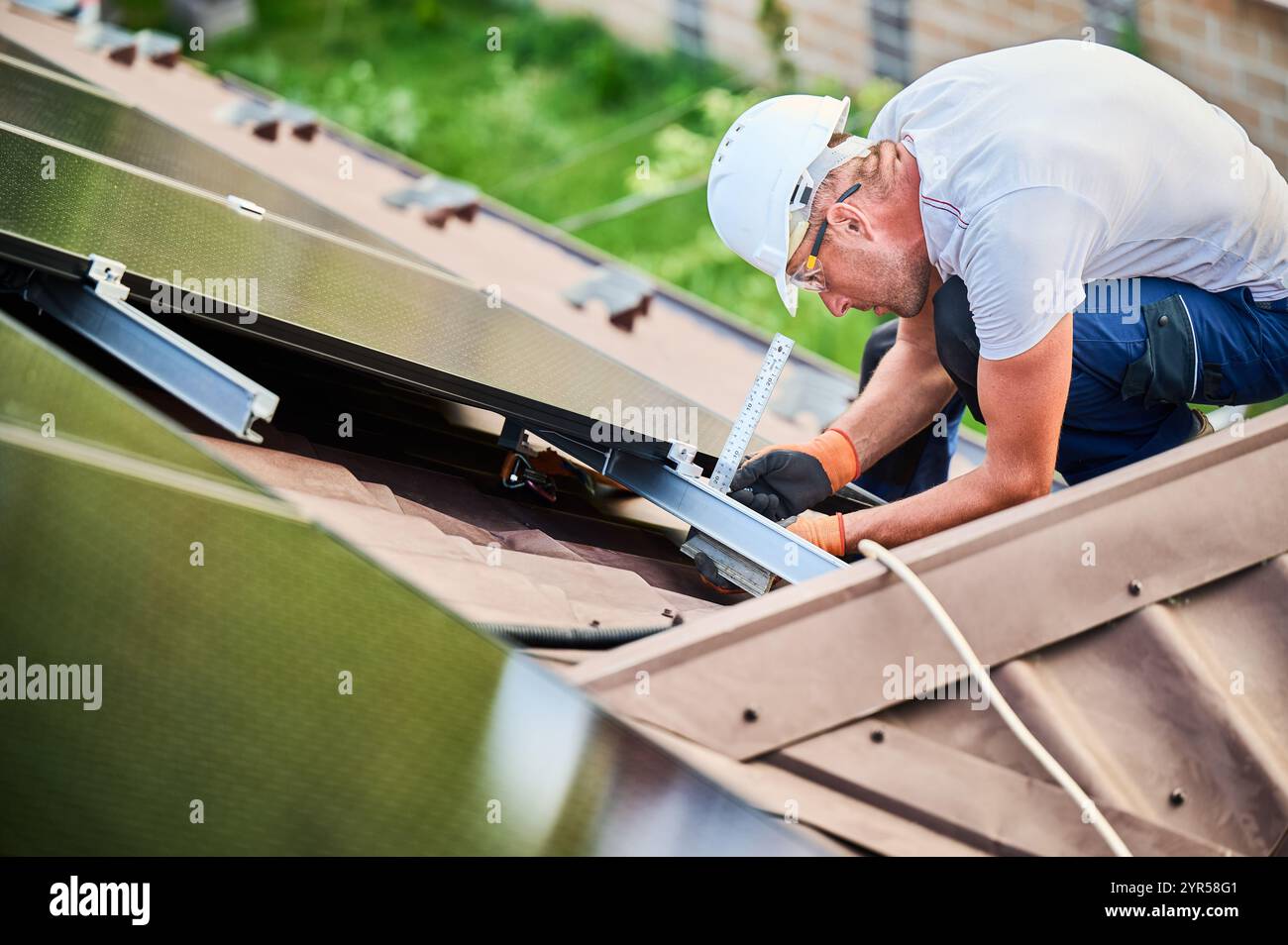 Worker building photovoltaic solar panel system on rooftop of house ...