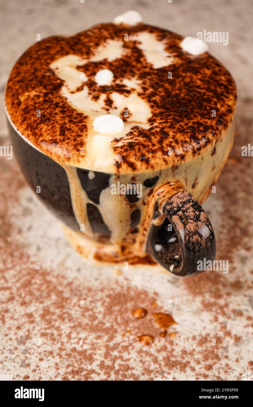 A rich cup of cocoa overflowing beyond the rim, topped with chocolate ...