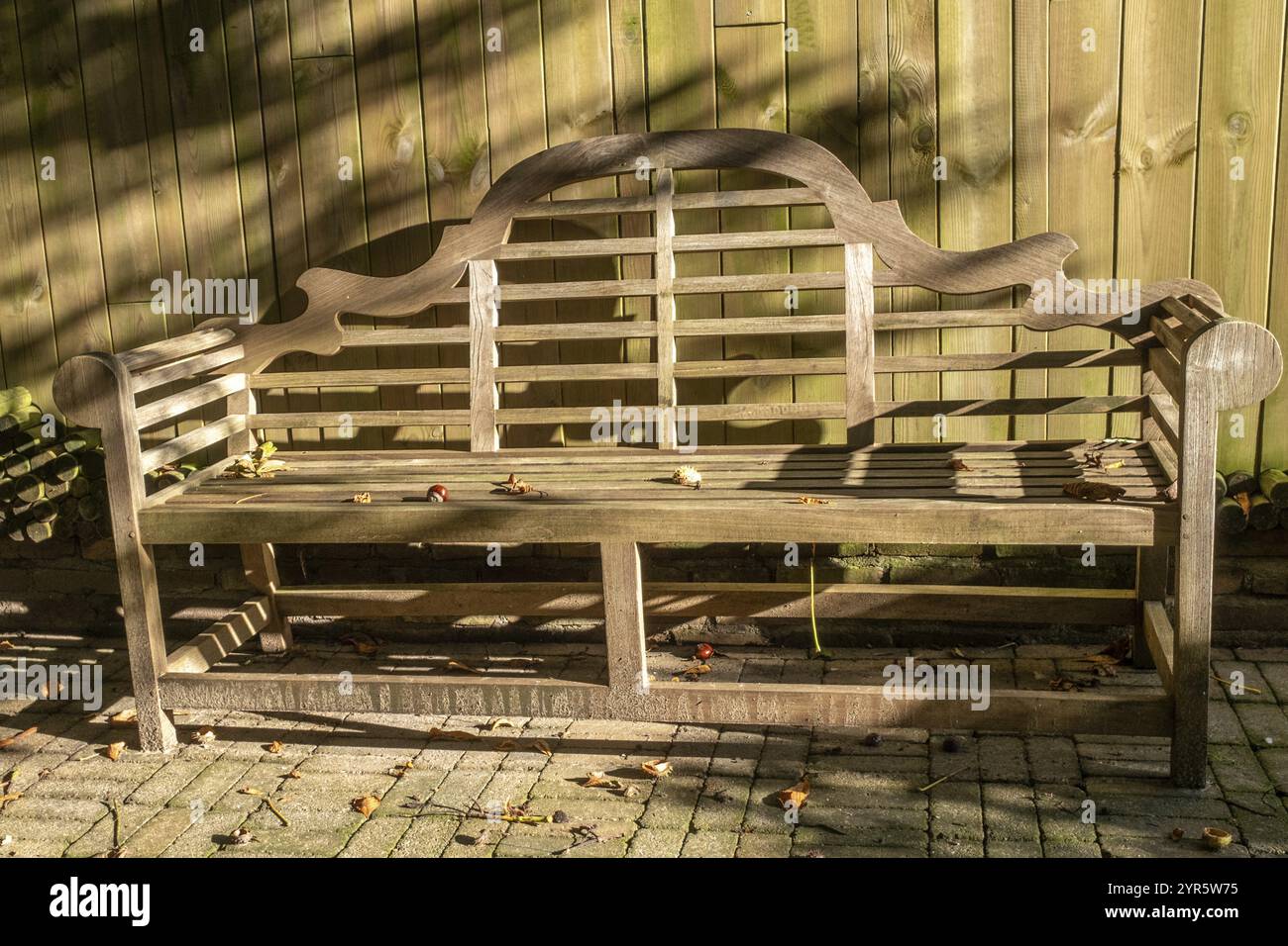 Wooden bench in front of wooden fence light and shade Stock Photo - Alamy