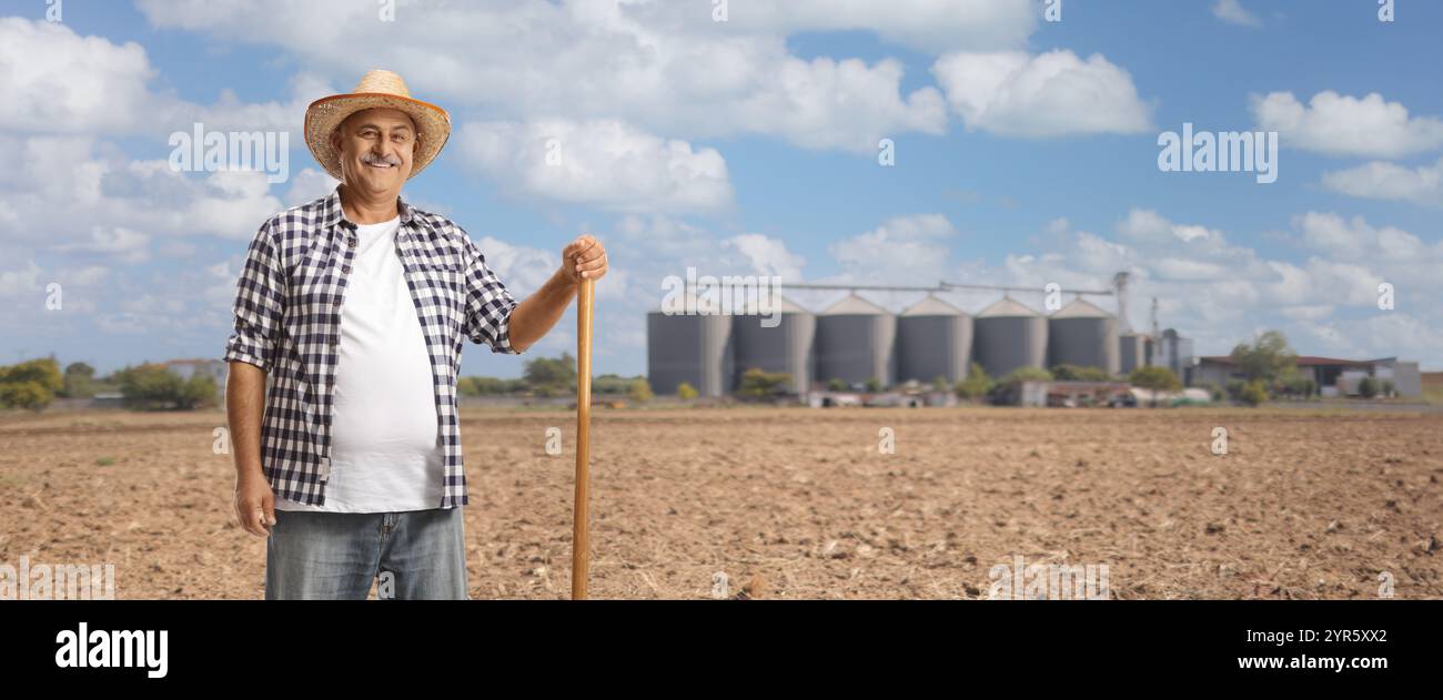 Mature farmer with a shovel on a field with agricultural silos Stock ...
