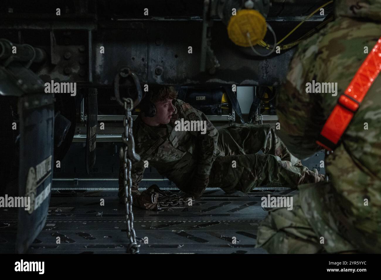 U.S. Air Force Liam McKey, 727th Air Mobility Squadron special handling technician, uses chains to tie down a R-11 Refueler truck onto a C-17 Globemaster III from the 67th Airlift Wing, Joint Base Lewis-McChord, Washington, at Royal Air Force Mildenhall, England, Nov. 29, 2024. Once the vehicle is aboard, loadmasters and special handling technicians secure it with chains and straps to prevent movement during flight. (U.S. Air Force photo by Staff Sgt. Jesenia Landaverde) Stock Photo