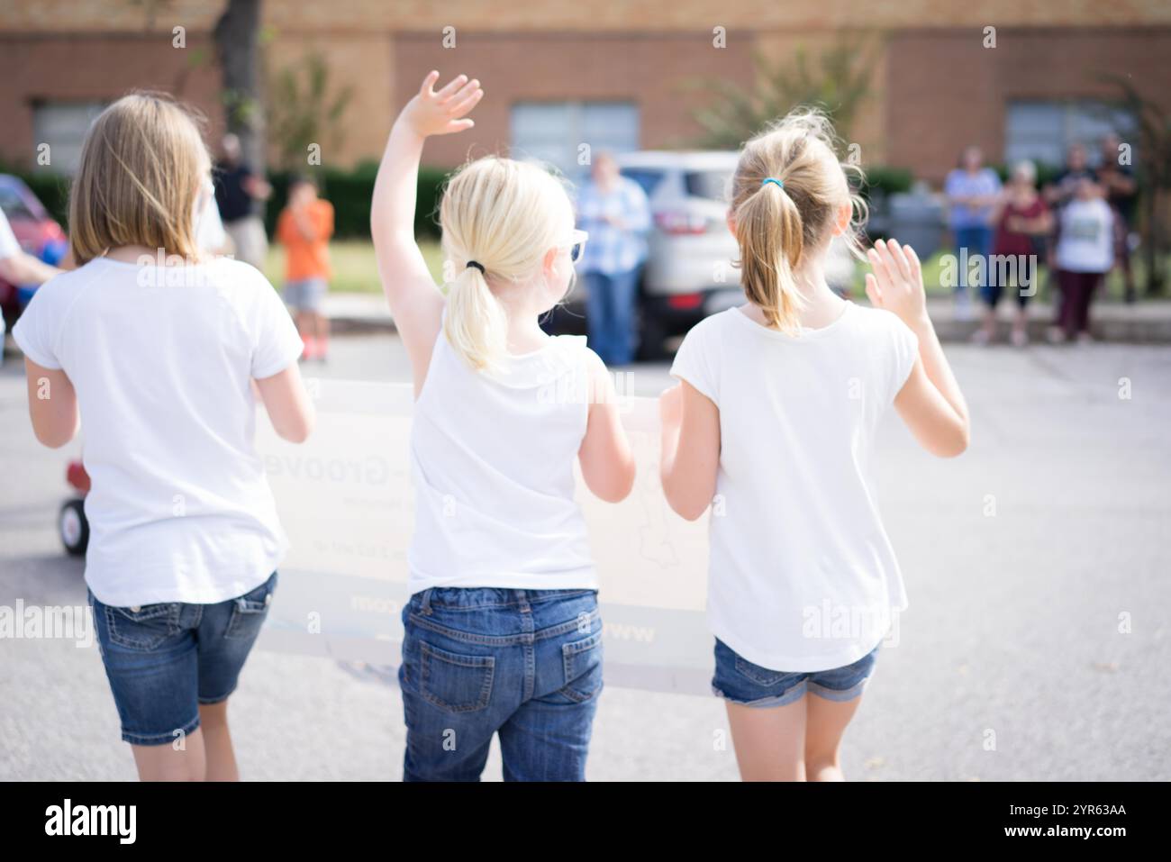 Young Girls Waving in Community Parade Stock Photo