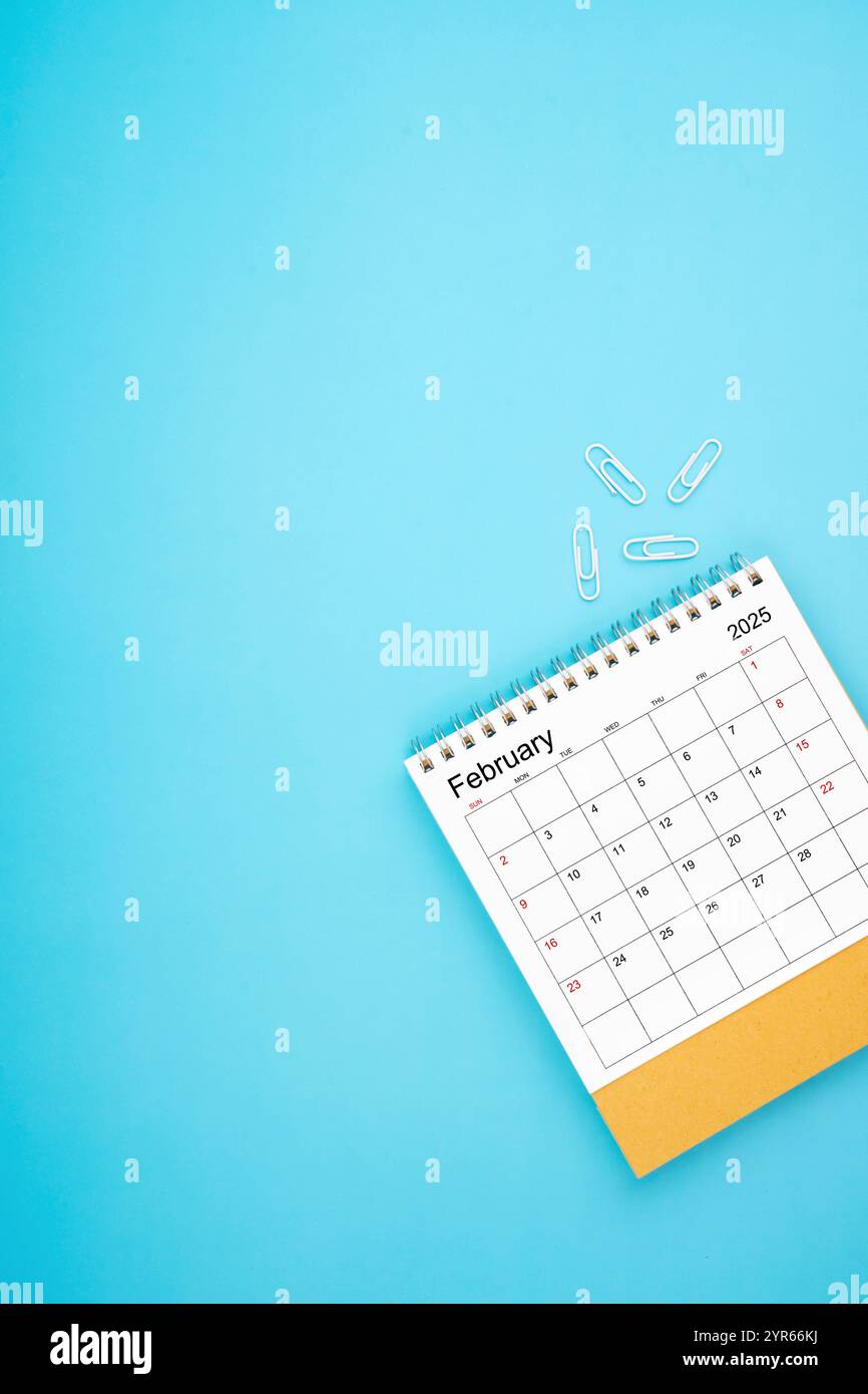Desk calendar for February 2025 and white paper clip on a light blue ...
