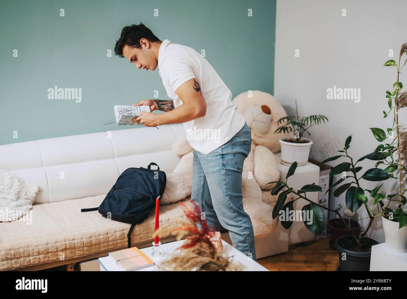 Young student organizing backpack in cozy living room setting Stock ...