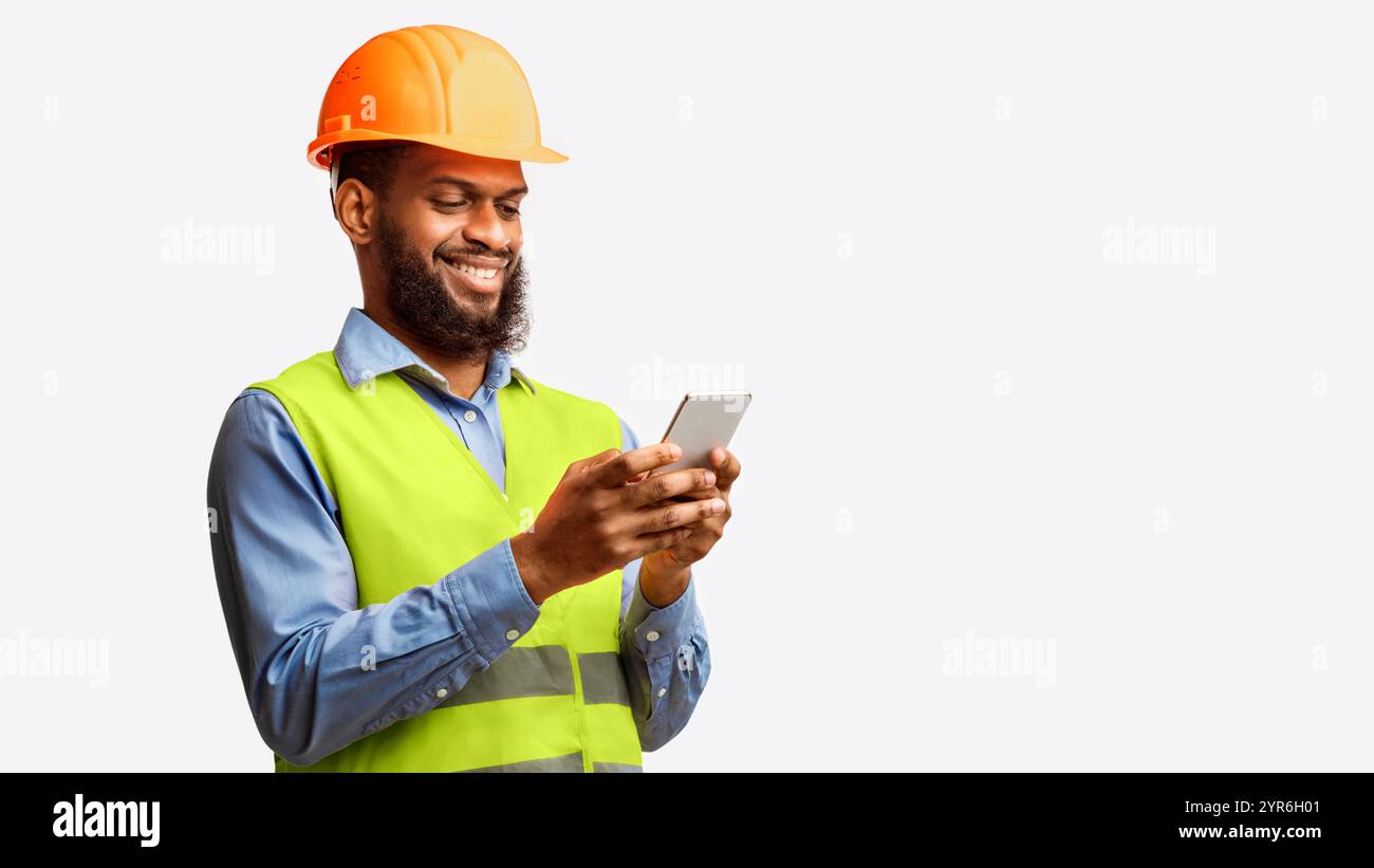 African Builder Worker Using Smartphone On White Studio Background, Panorama Stock Photo