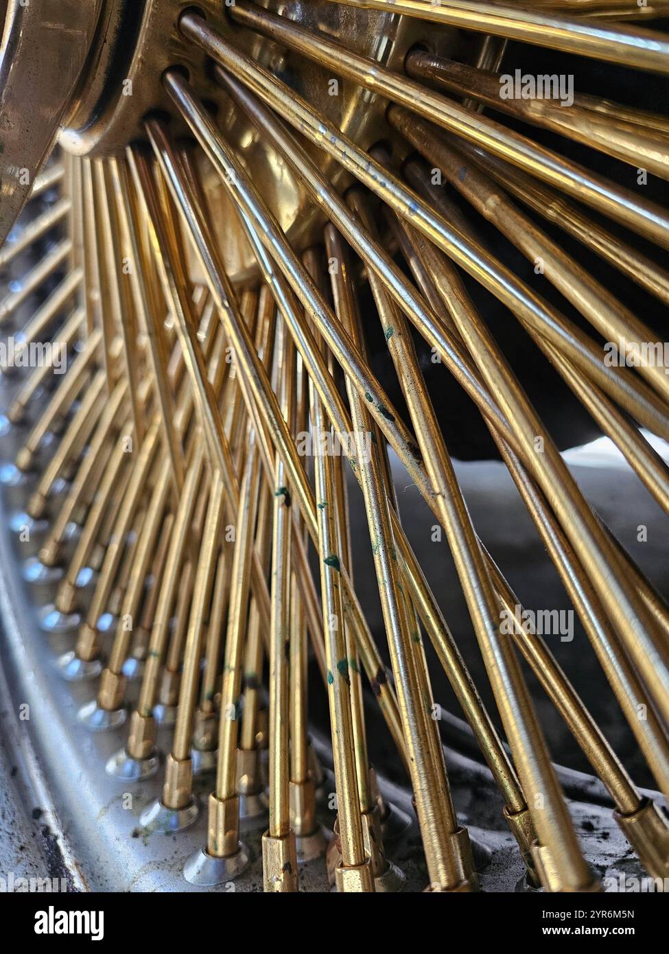 'Close-up of golden spokes of a classic car wheel, showcasing intricate details and metallic shine. Perfect for automotive enthusiasts and design them - Smartphone Captured Stock Image