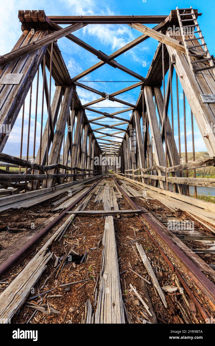 The bridge is old and rusted, with a wooden structure and a metal rail ...
