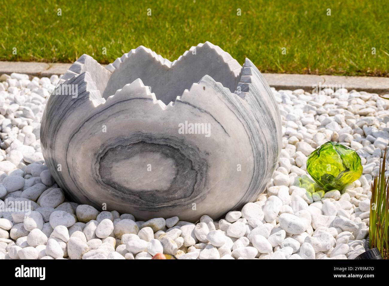 Large broken marble egg as a water fountain in a stone bed. High quality photo Stock Photo