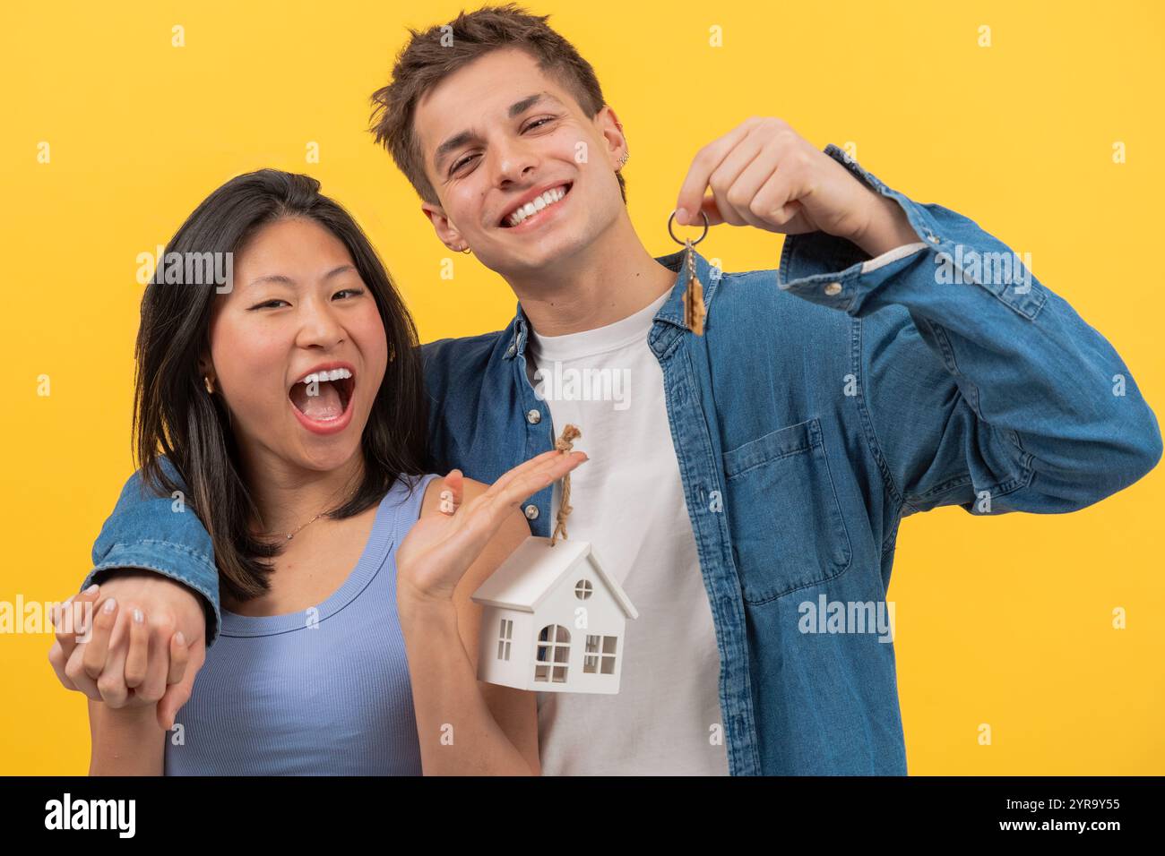 Happy couple holding house keys and small model house, celebrating new ...