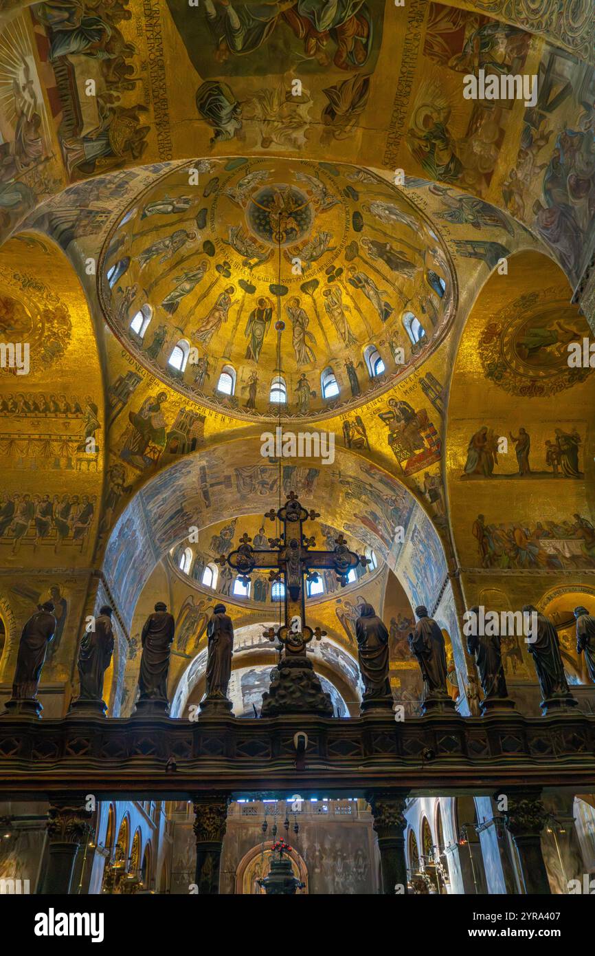 The silver and bronze crucifix on the Gothic altar screen in St. Mark's Basilica in Venice, Italy.  On either side are statues of the Virgin and the T Stock Photo