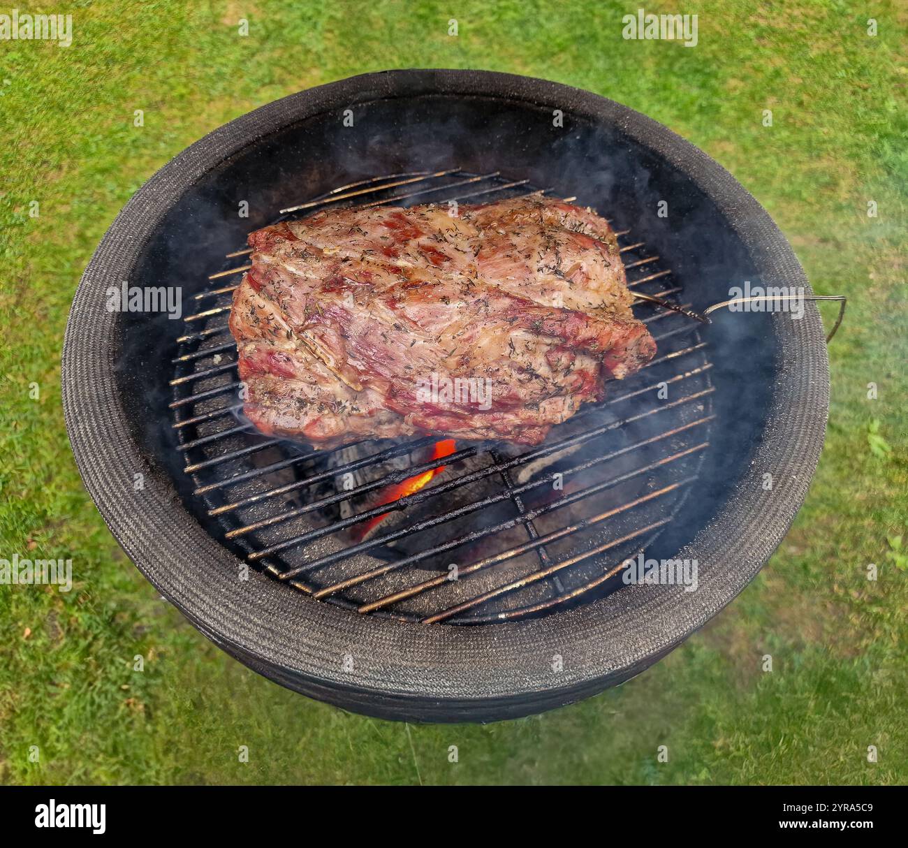 Close Up of barbecue with charcoal fire on which a beautiful pork tenderloin is nicely browned and baked with a temperature probe to measure the core Stock Photo