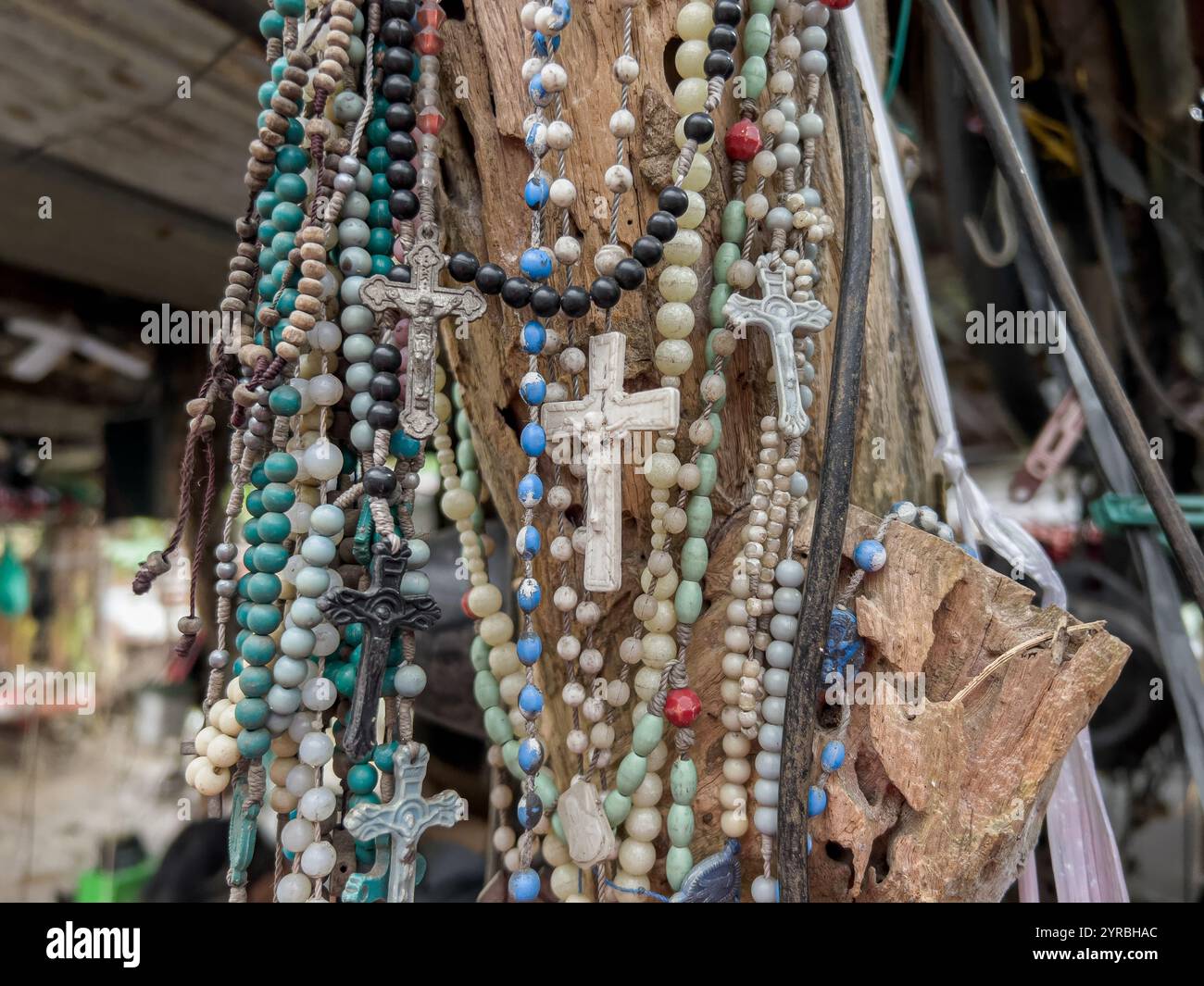 Collection of several Christian prayer beads, rosaries hanging on a tree trunk in the Philippines, Catholic religion, Southeast Asia country - Smartphone Captured Stock Image