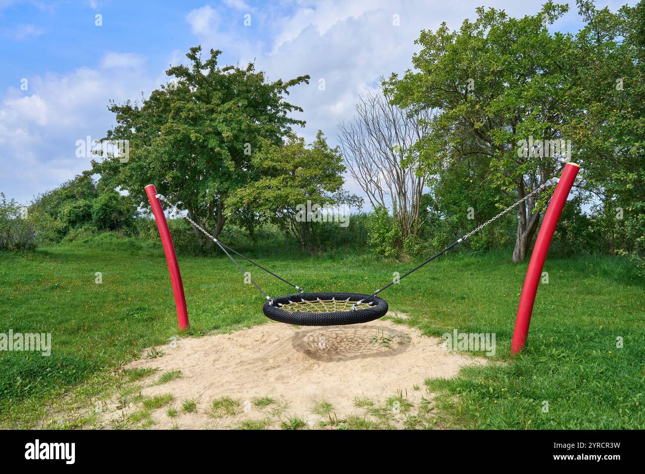Nest swing on a meadow with trees, attached to two bent posts Stock Photo
