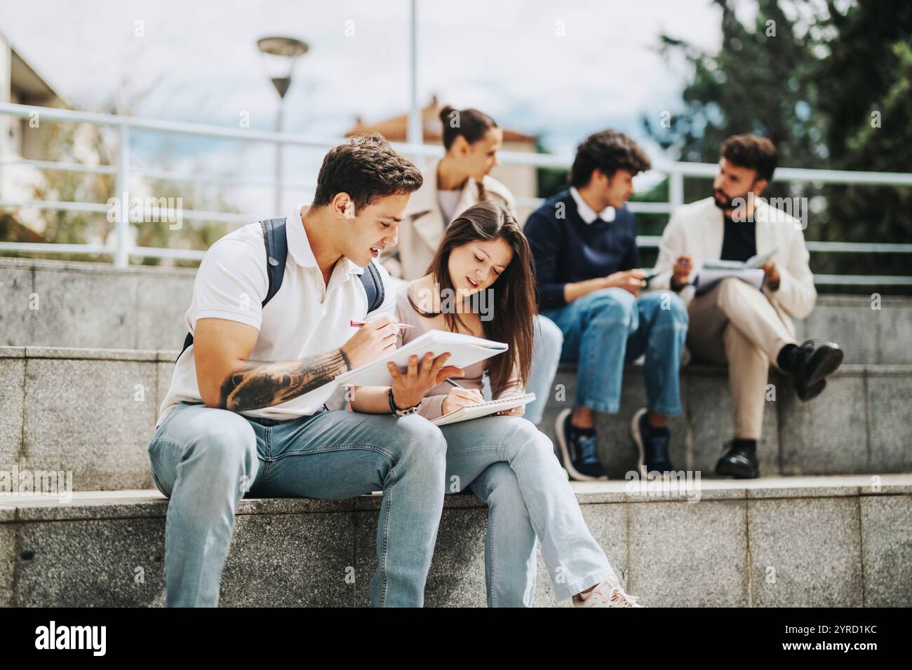 Students collaborating with professor outdoors on university campus Stock Photo