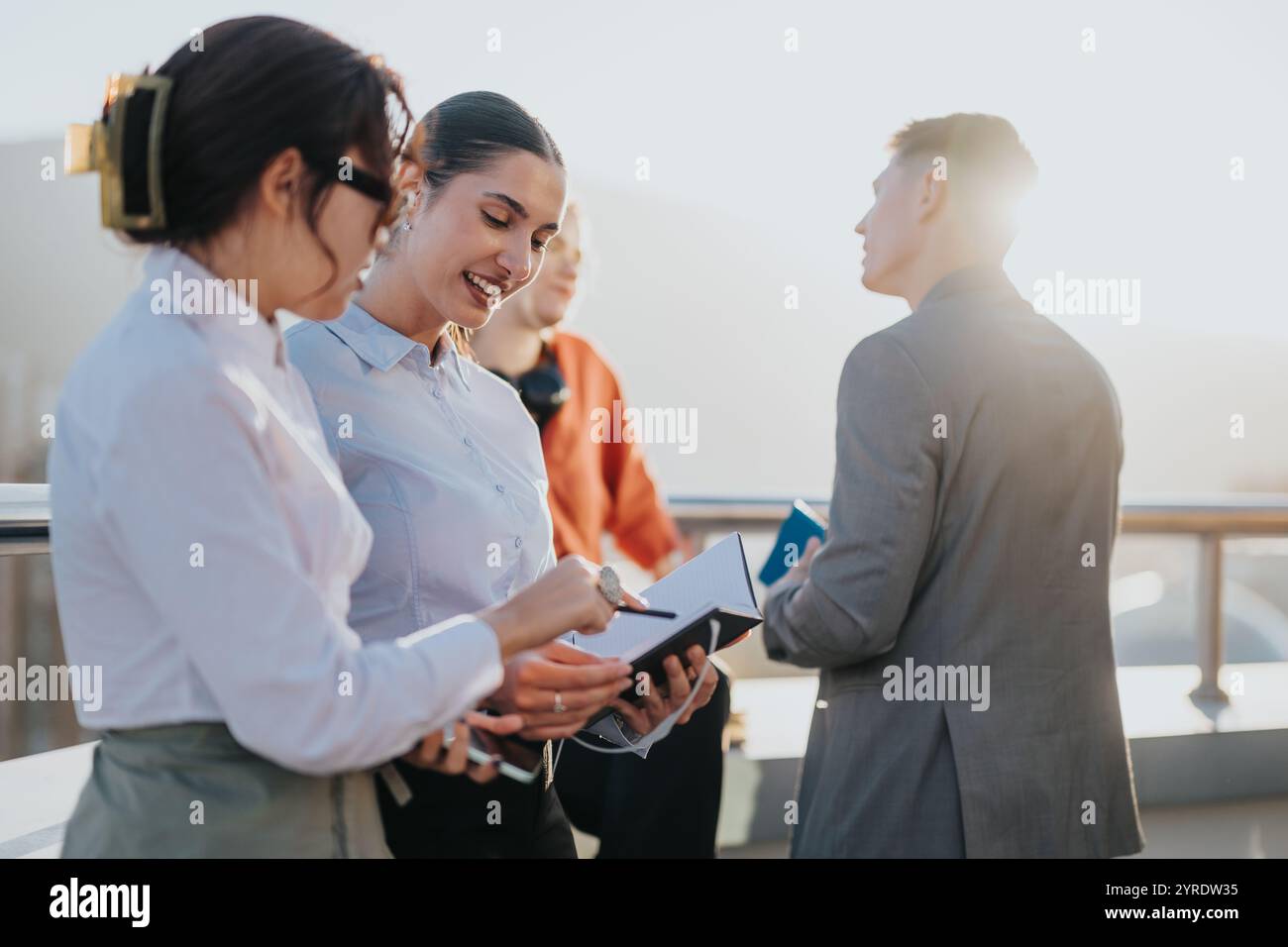Diverse business team collaborating on rooftop during sunset Stock Photo