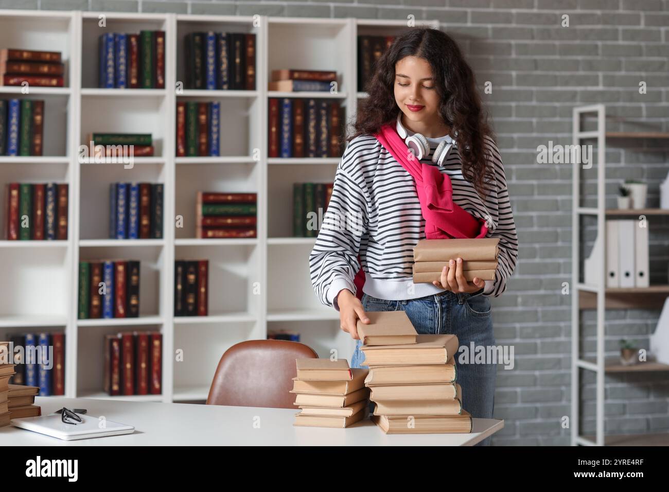 Female student with books in library Stock Photo - Alamy