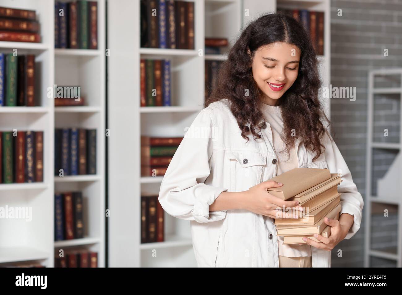 Female student with stack of books in library Stock Photo - Alamy