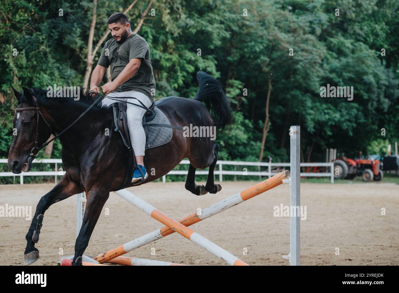 Man riding horse during equestrian jump training outdoors in arena ...