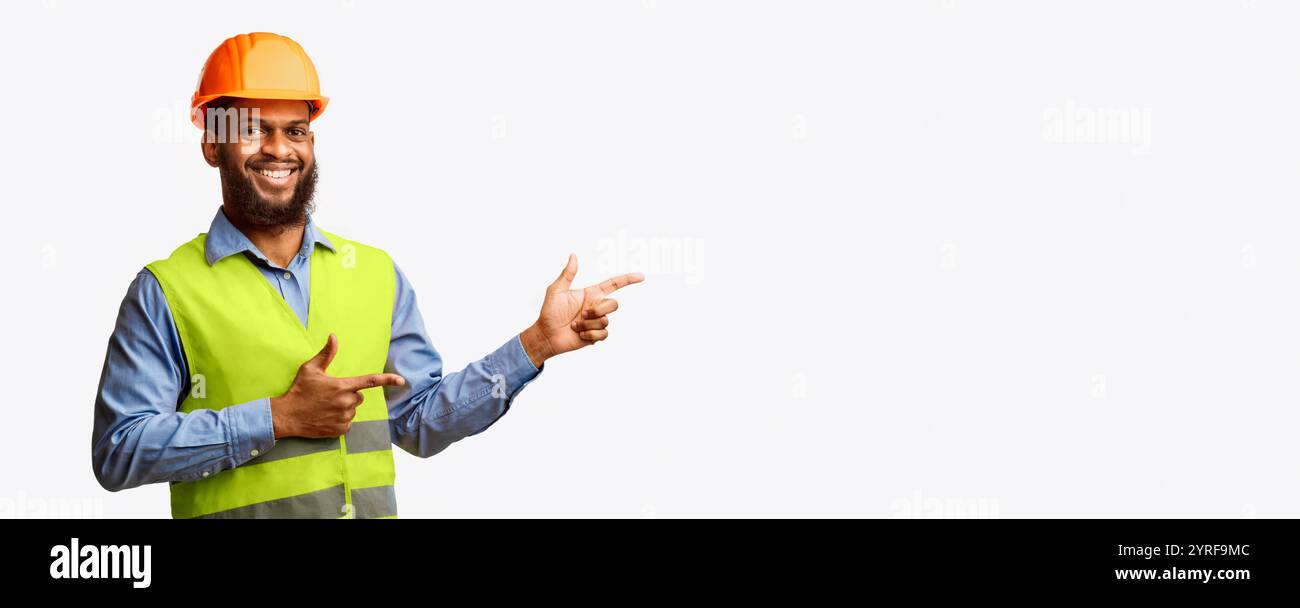 Builder Guy In Uniform Pointing Fingers Aside On White Background Stock Photo