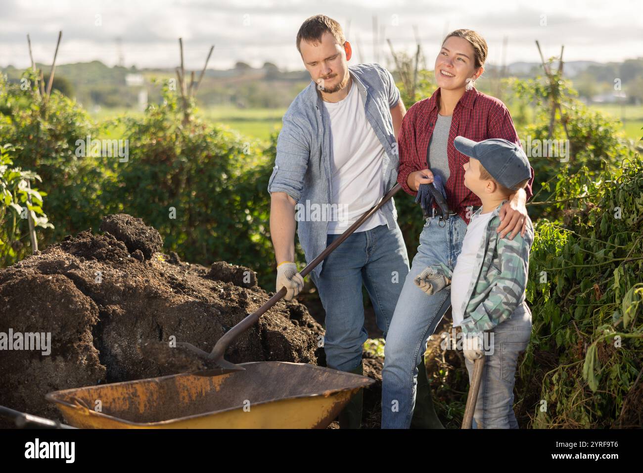 Man woman and boy putting soil in wheelbarrow Stock Photo - Alamy