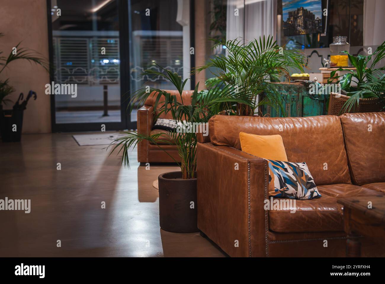 The interior features rich leather sofas with colorful cushions, lush ...