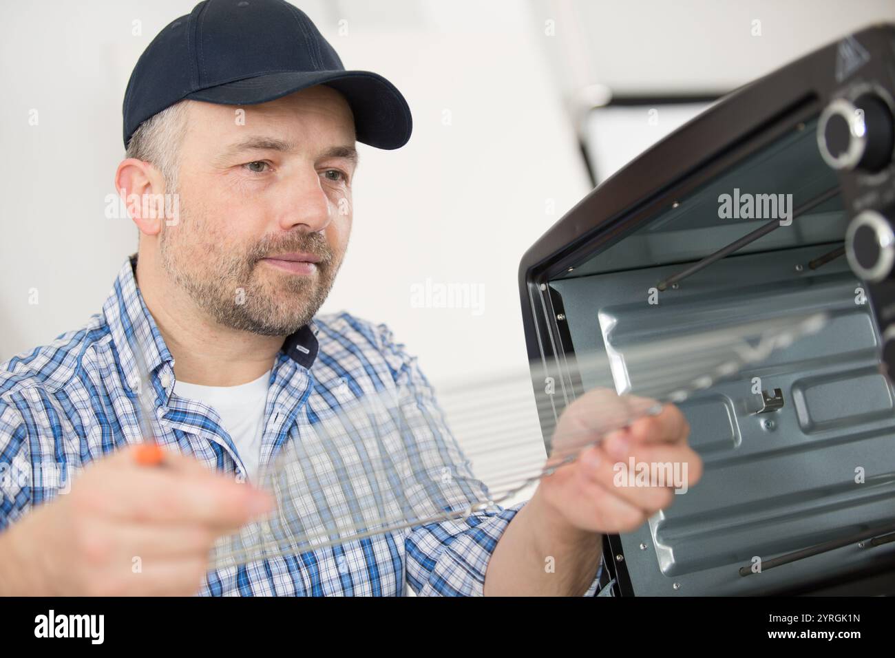 serviceman in overall working on fridge Stock Photo