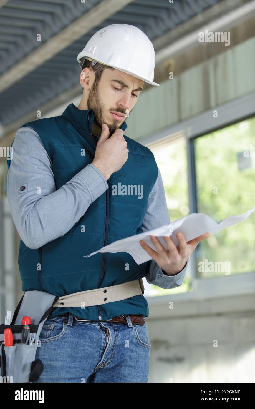 young builder contemplating plans Stock Photo