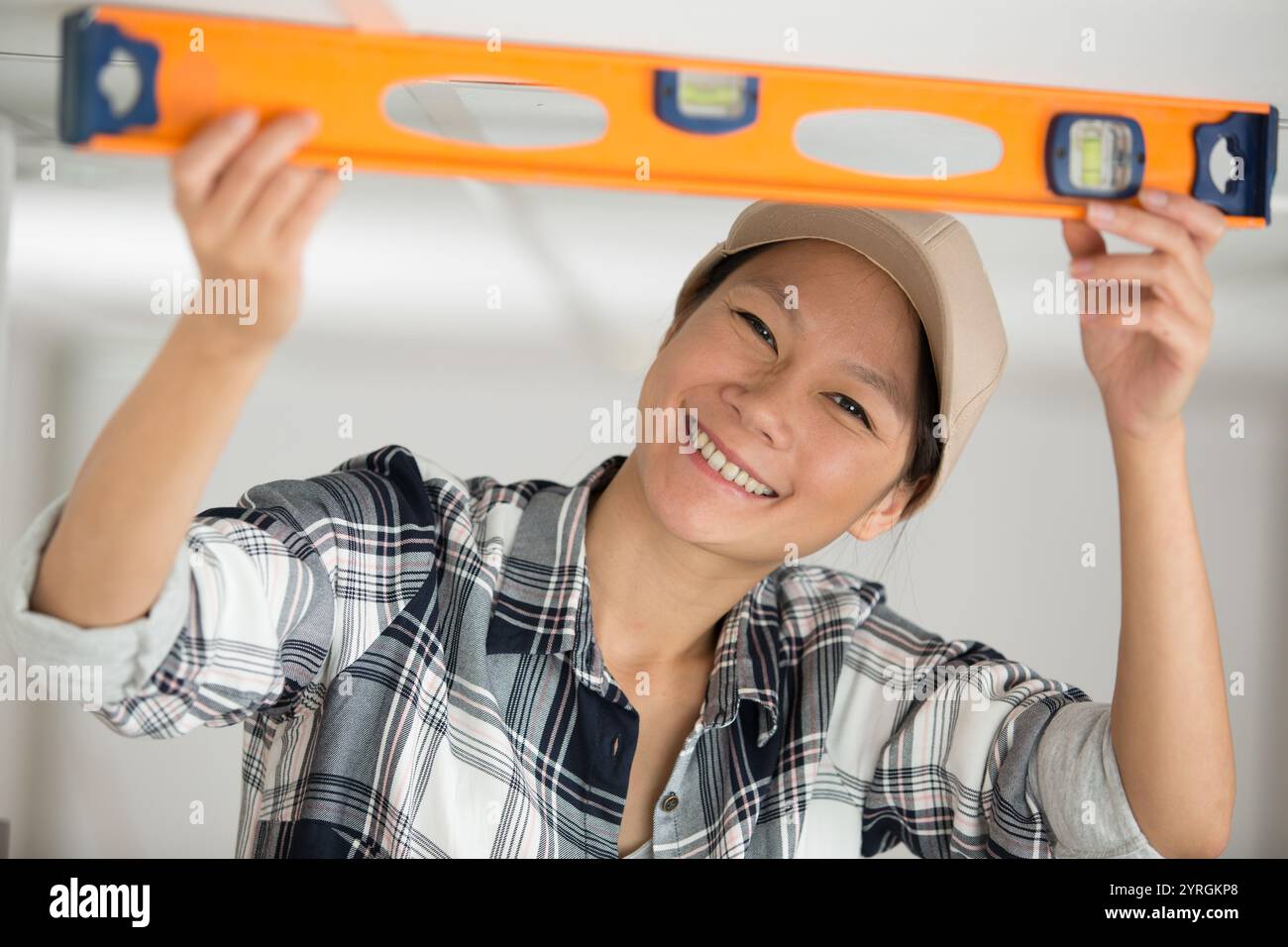 smiling female worker using a spirit level Stock Photo