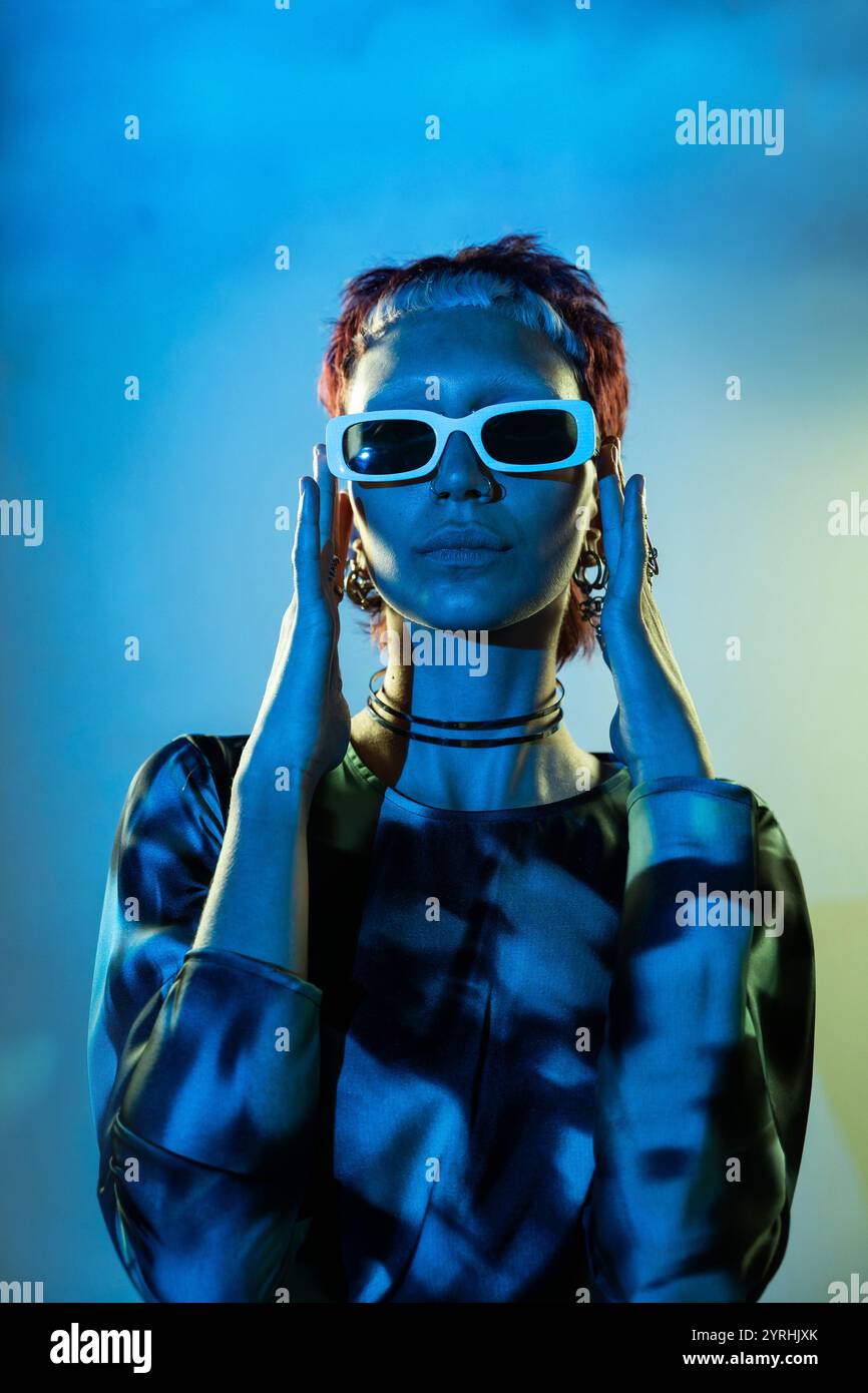 Futuristic woman styled in futuristic blue attire, framed against a gradient blue background Stock Photo