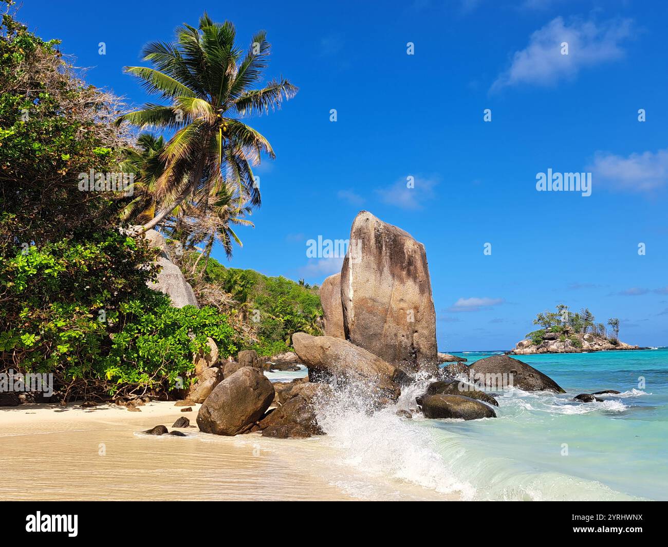 Waves splashing against rocks on a beach in Mahé, Seychelles. Stock Photo
