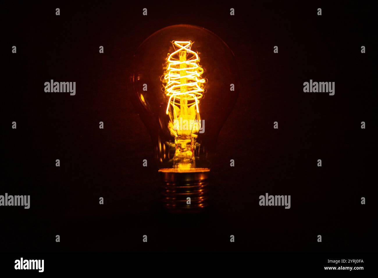 Vintage incandescent light bulb glows on black background. Think different, concept. Creative idea. Electricity Stock Photo