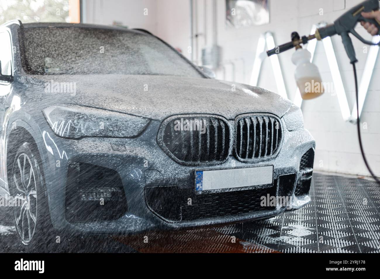 Car is washed at a professional car wash. Man washes a car with foam ...