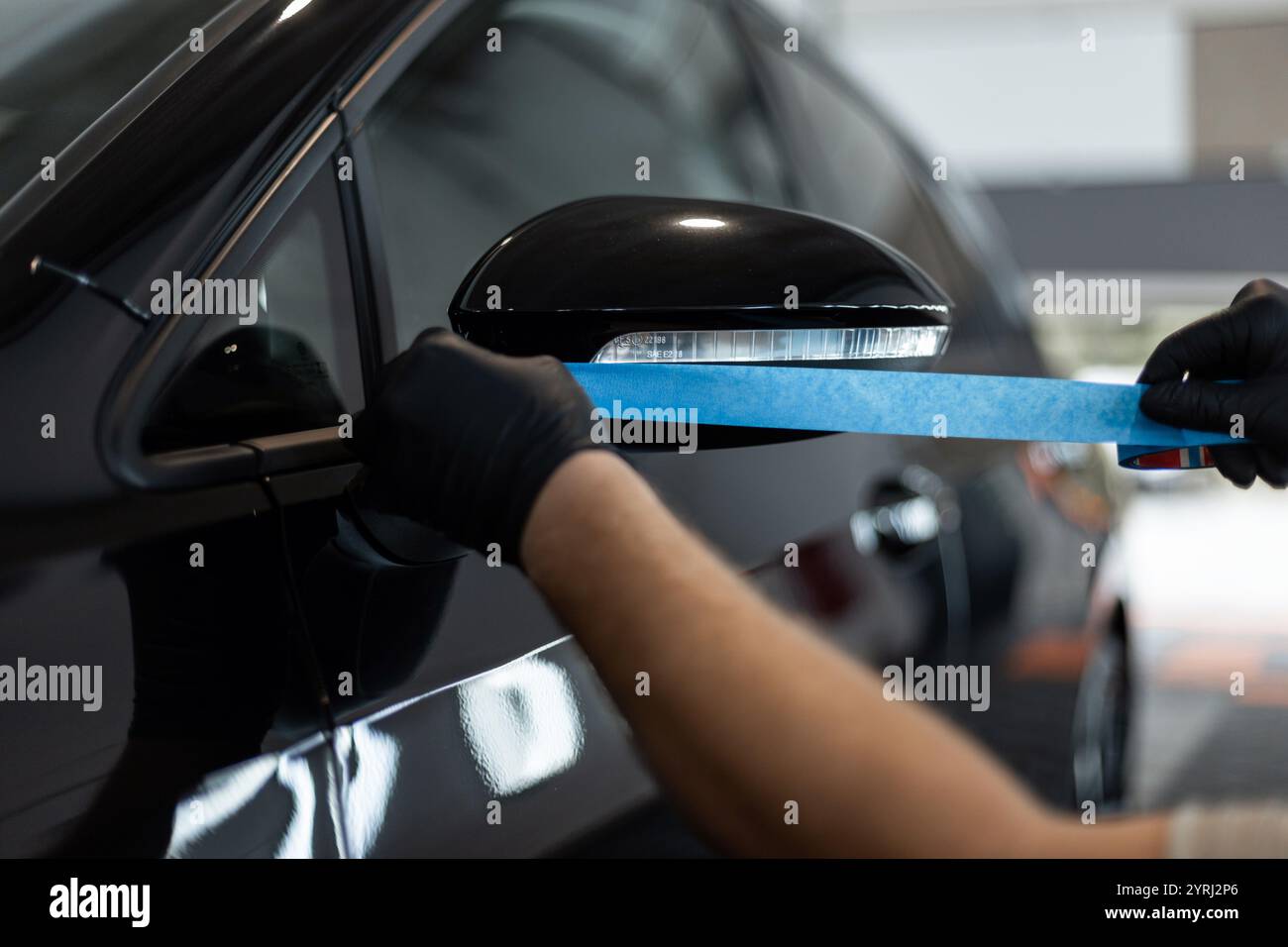 professional man tapes a car with masking tape before polishing. Preparation before polishing Stock Photo