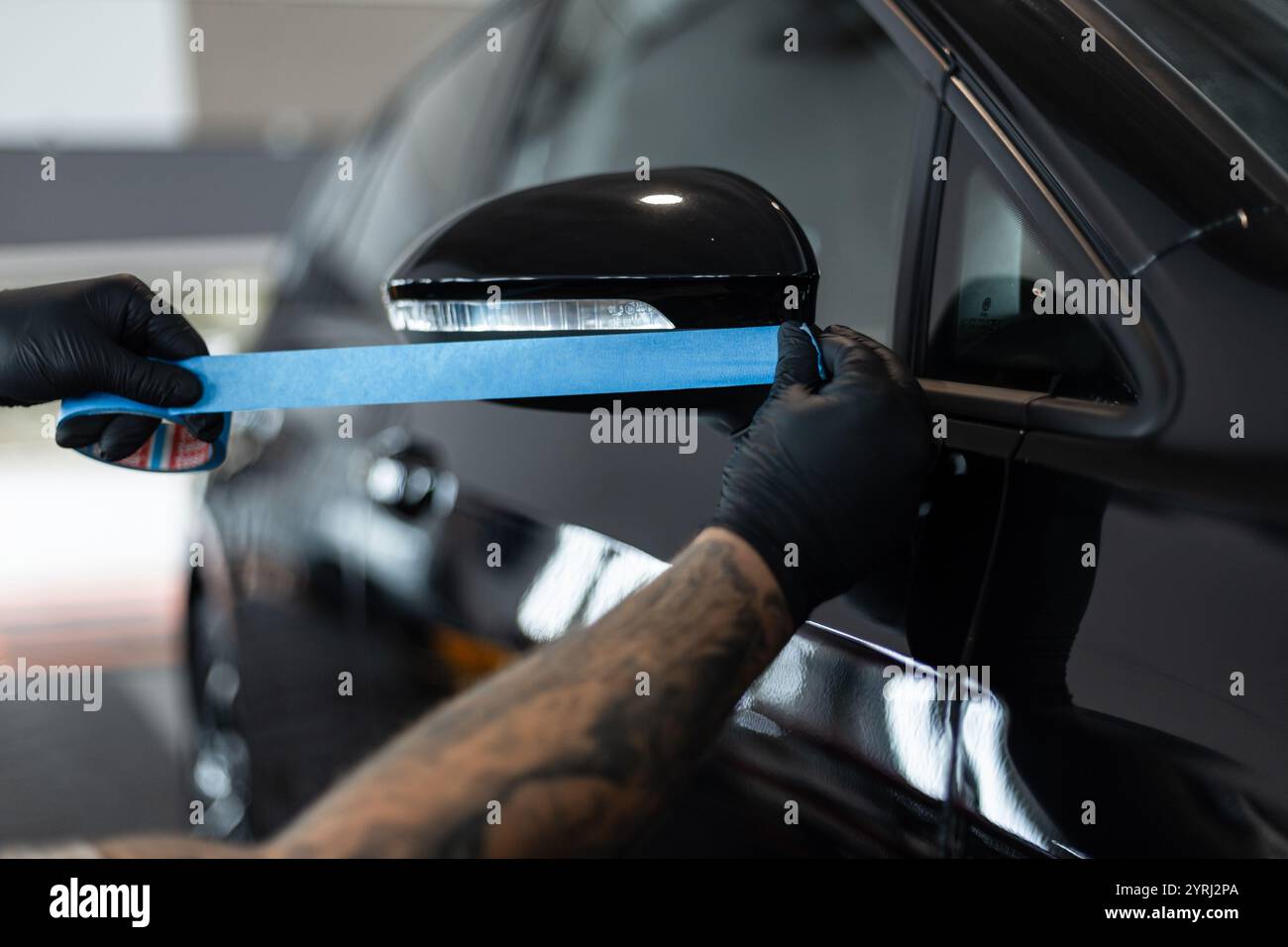 professional man tapes a car with masking tape before polishing. Preparation before polishing Stock Photo