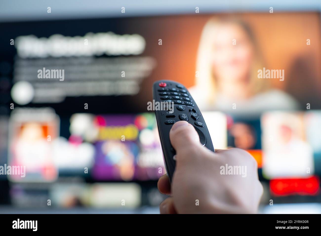 Person's hand changing tv programs by using smart tv remote control. Close up view. Stock Photo