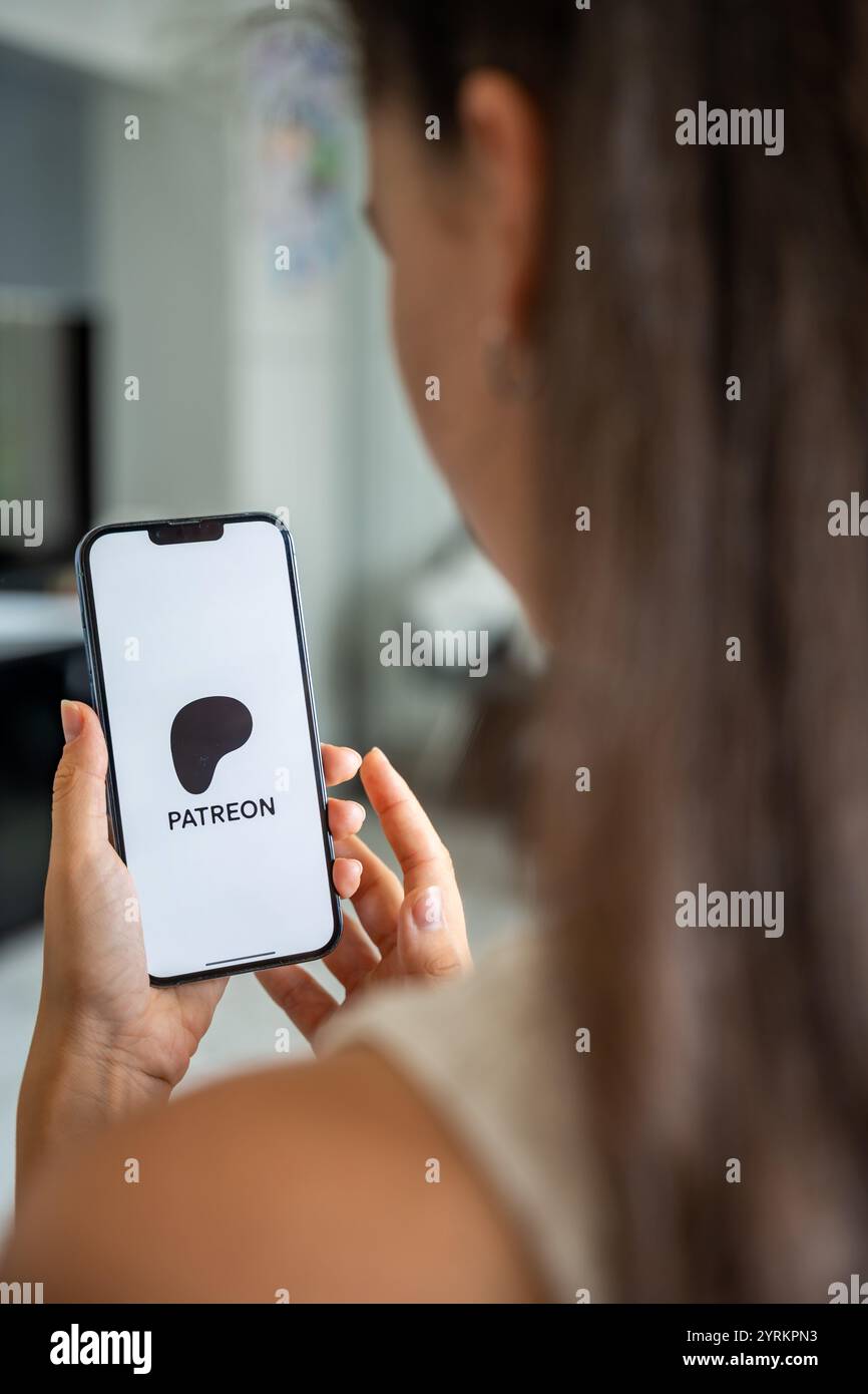 Prague, Czech republic - May 2, 2024: Woman holding iPhone with logo of application Patreon on the screen, using mobile application for business home Stock Photo