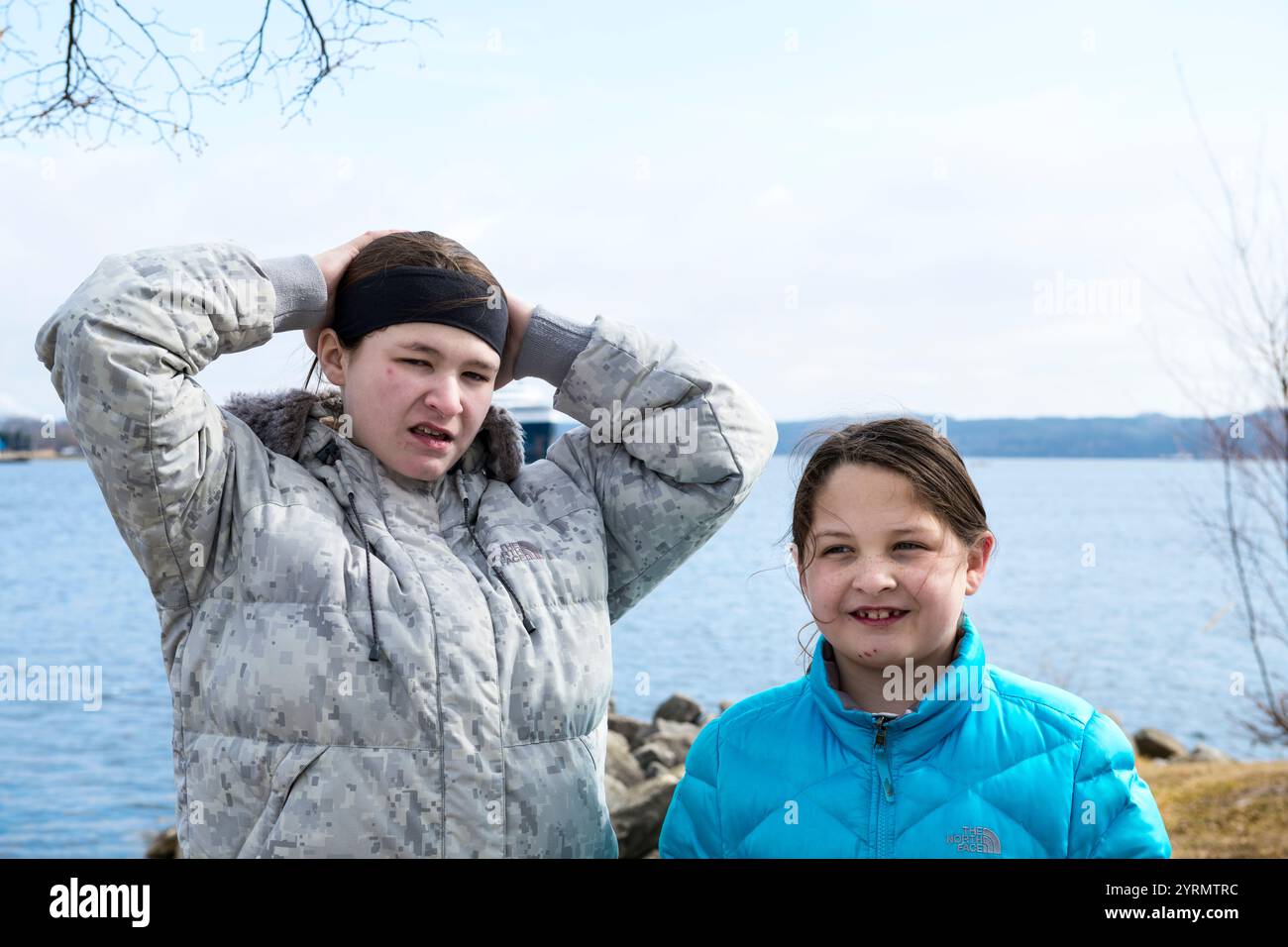 Sisters posing for the camera with Hamline Lake behind during a hike in Ludington State Park in early spring near Ludington, Michigan, USA.  Ludington Stock Photo