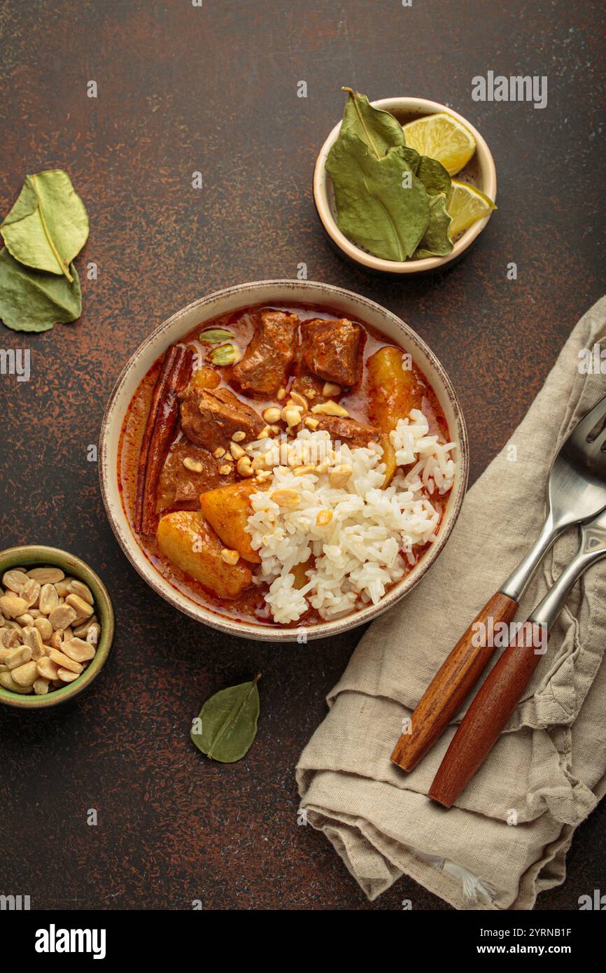 Delicious massaman curry with beef, potatoes, rice, and peanuts is served in bowl top view, Thai cuisine Stock Photo