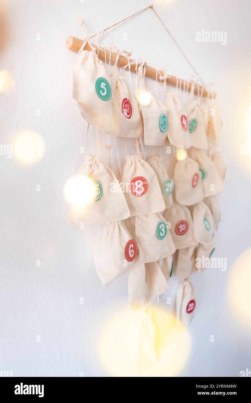 DIY Advent calendar made with fabric bags hanging from a wooden rod, and with the numbers 1 to 24 stick to the bags. Stock Photo