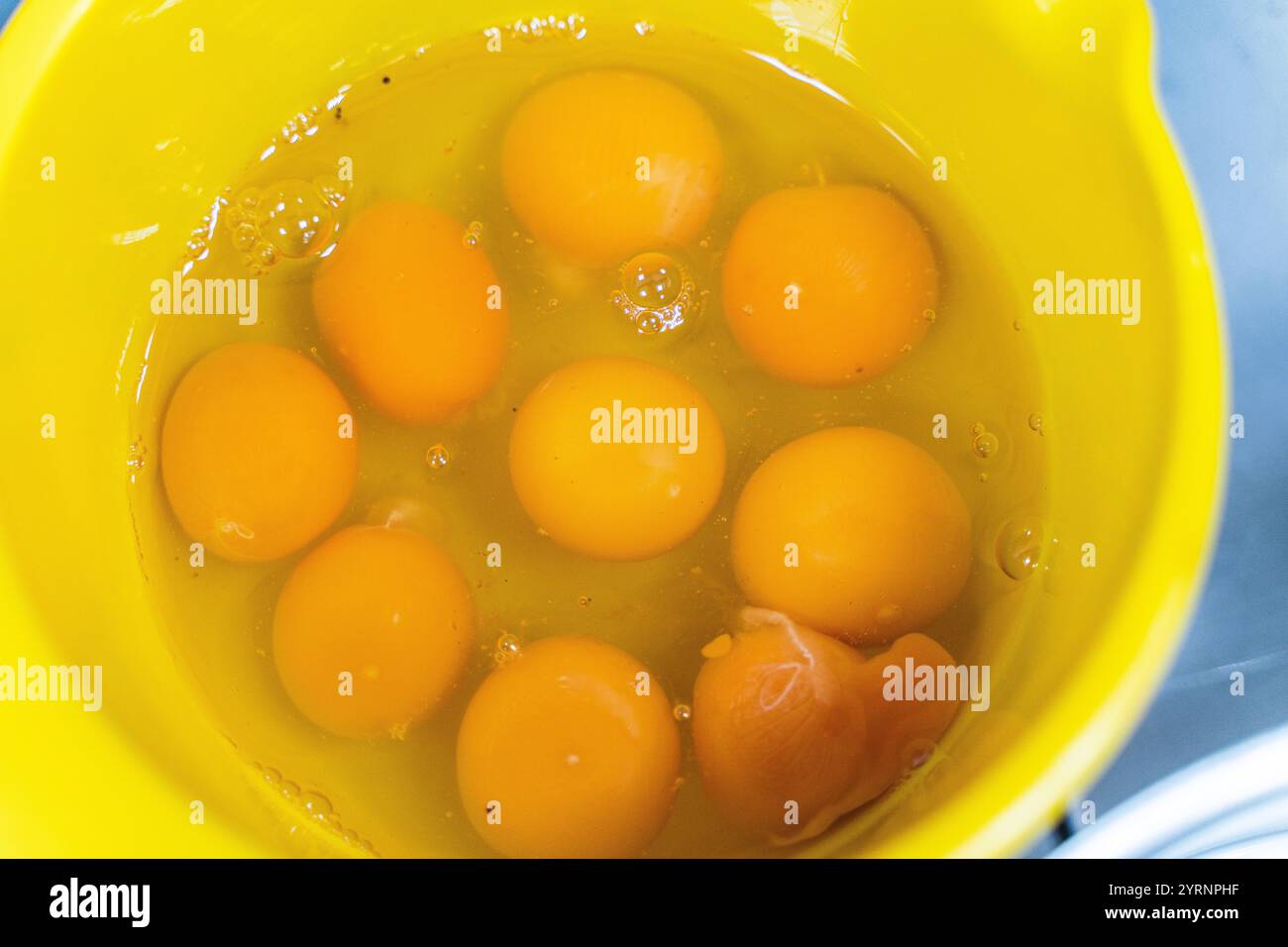 Egg yolks and whites in a yellow bowl. Lots of broken eggs in a bowl. High quality photo Stock Photo