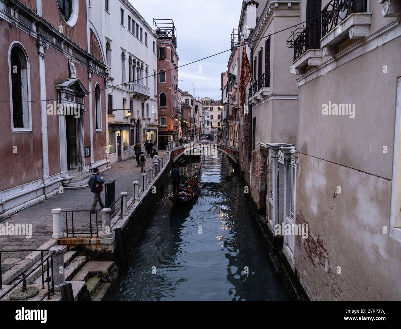 Tourists on a Gondola ride along a water canal on the streets of Venice, Italy Stock Photo