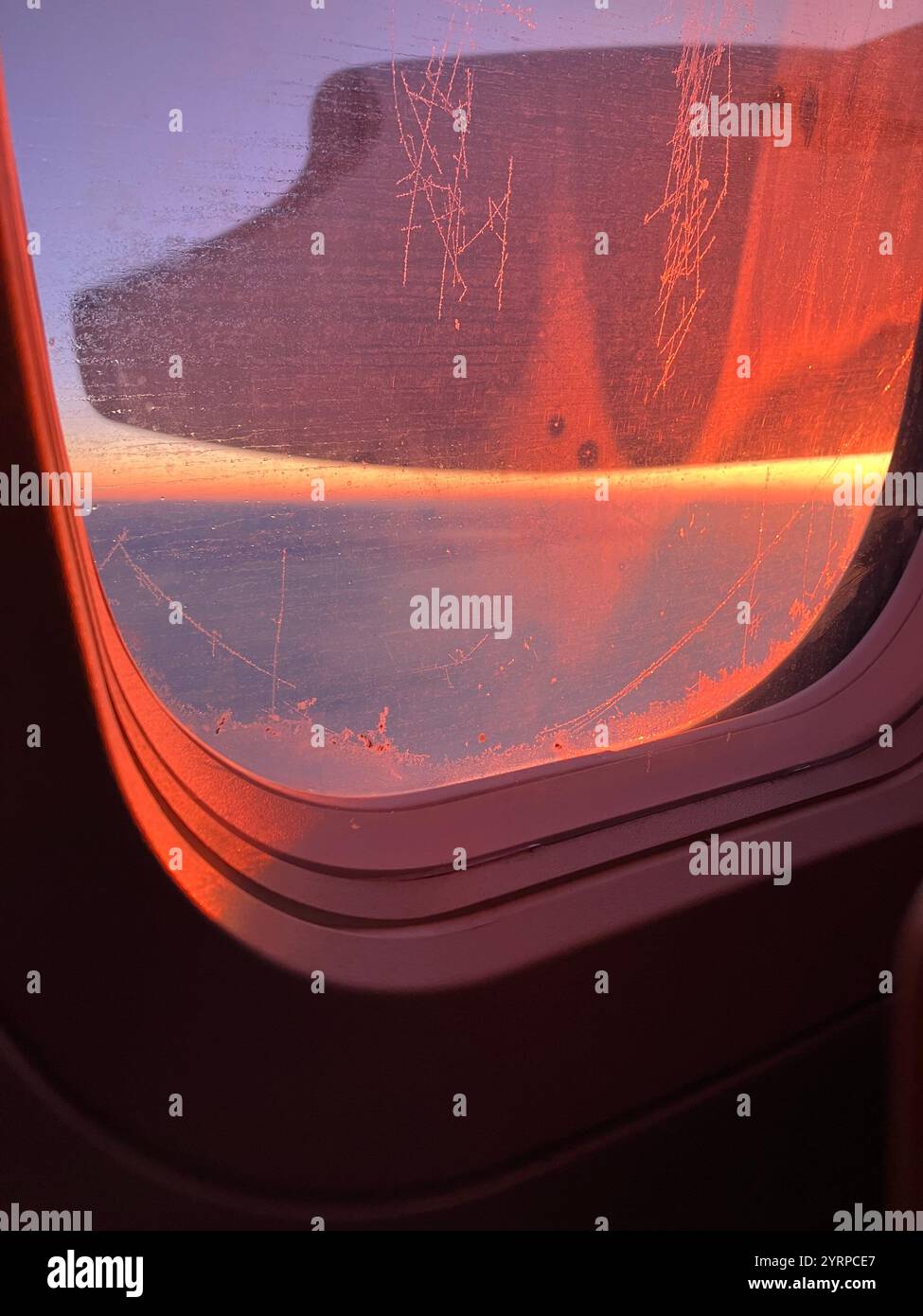 A view of the sunrise from a plane window, featuring soft colors and clouds on the horizon. - Smartphone Captured Stock Image