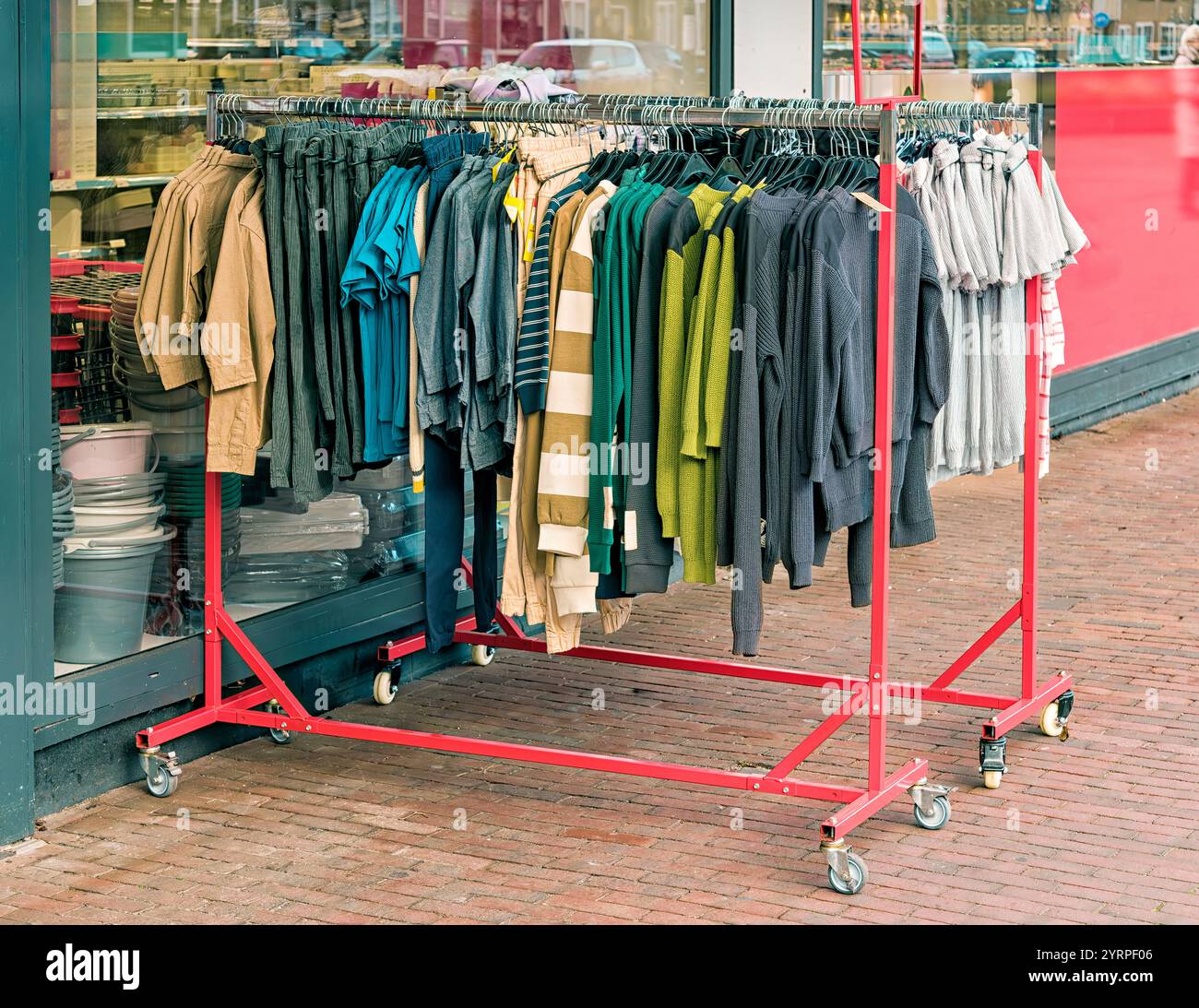 clothes rack full of sweaters in various colors is outside a shop ...