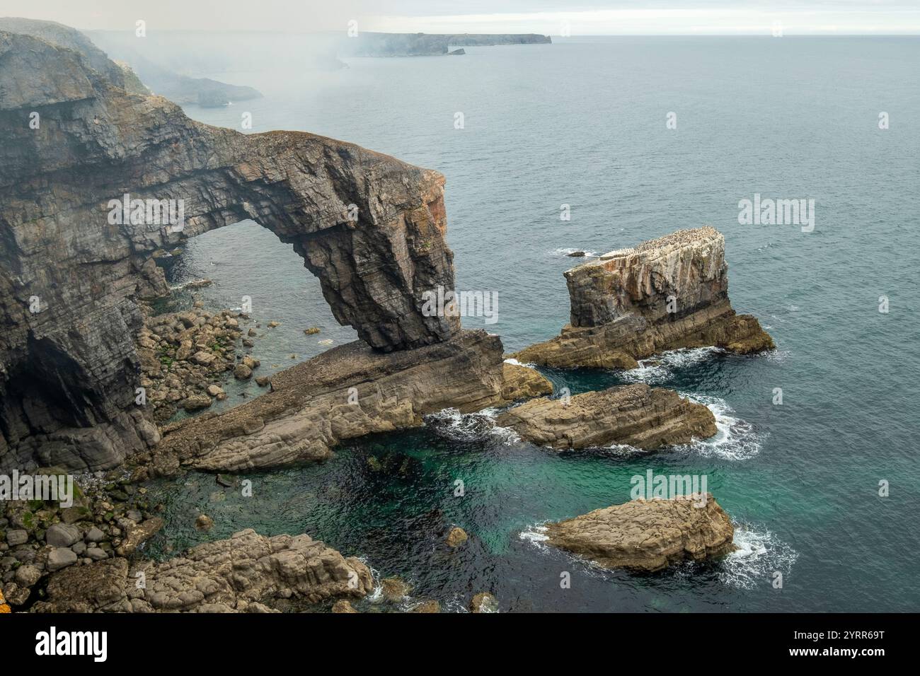 Mist rolls off the cliff at the Green Bridge of Wales, Pembrokeshire. Carboniferous Limestone arch Stock Photo