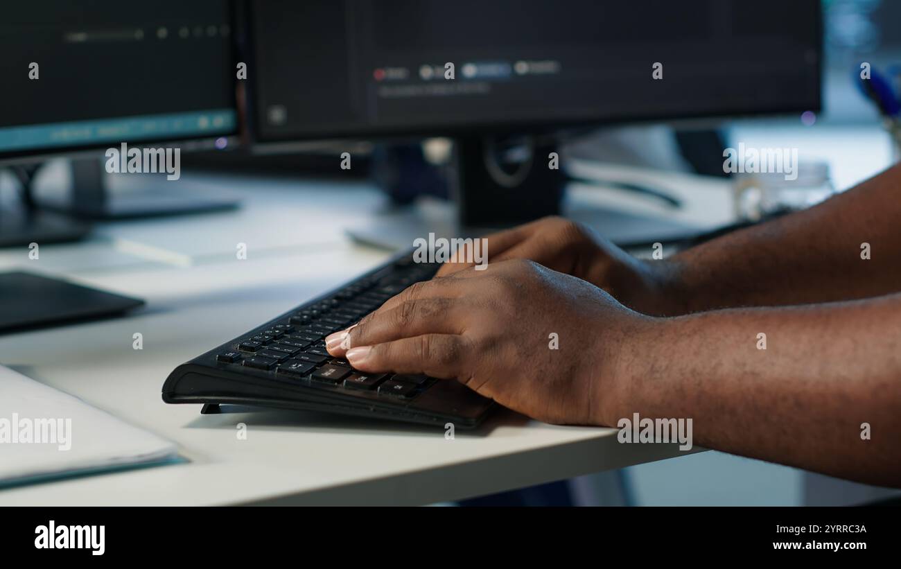 Programmer in server farm workspace protecting data threatened by hacking attacks on computers. IT professional writing code, safeguarding data center from unauthorized access, camera A close up Stock Photo
