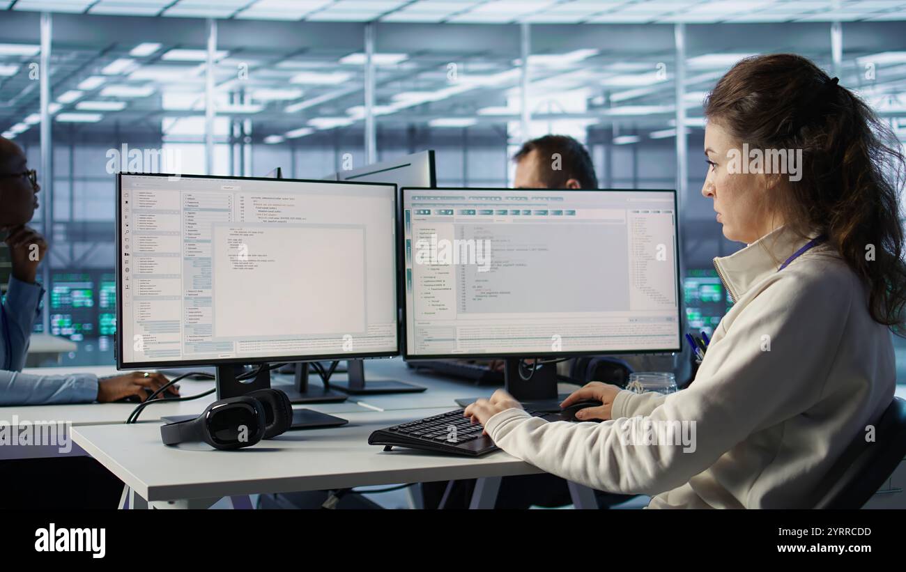 Computer scientist working in diverse computer network security data center workplace, ensuring optimal performance. Software developer monitoring energy consumption across server racks Stock Photo