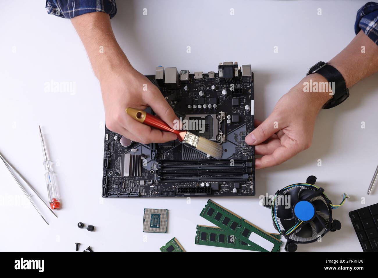 Man Installing Computer Man installing computer chip onto motherboard at white table, top view ...