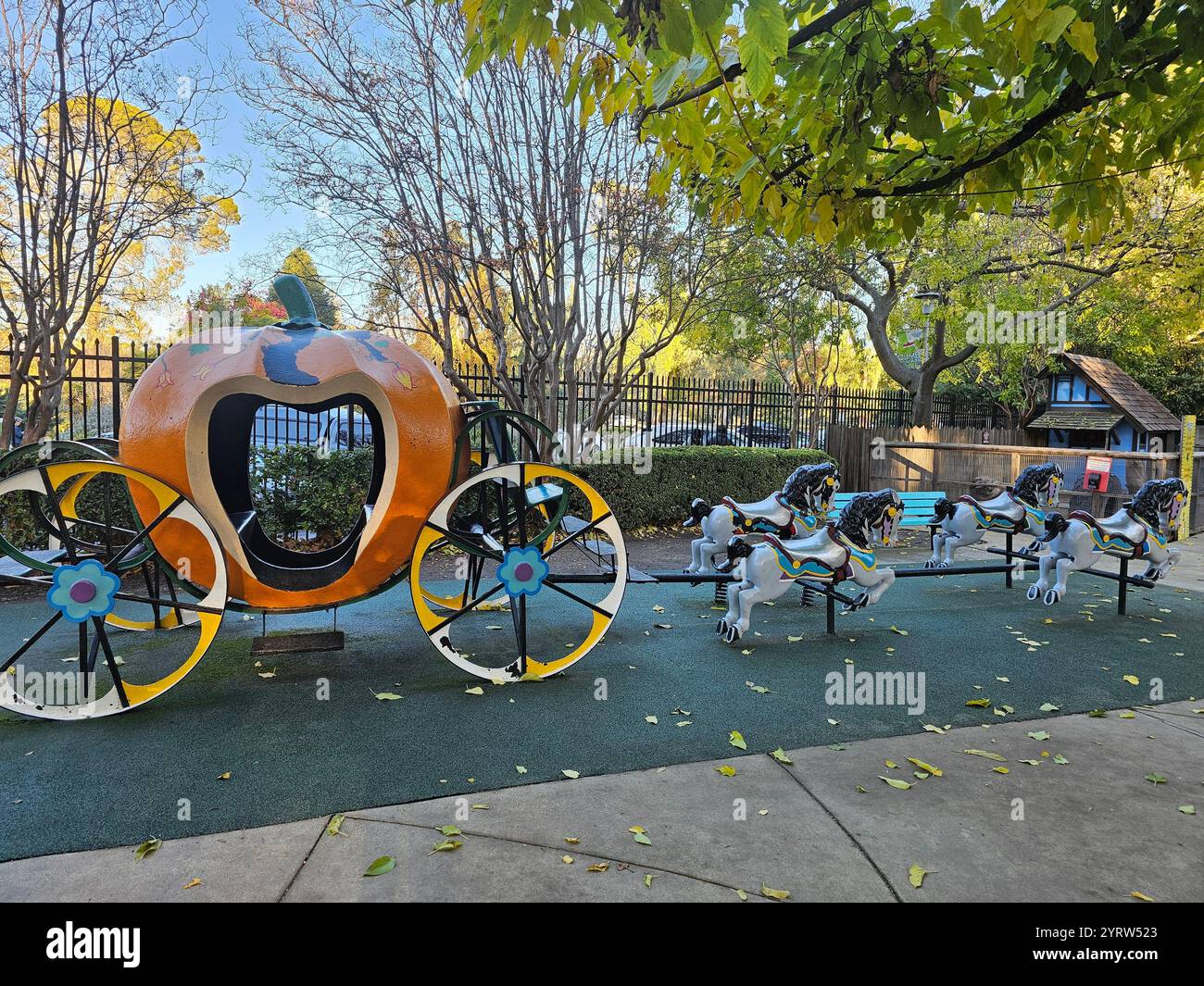 A charming pumpkin-shaped carriage with decorative horse sculptures in a park setting, surrounded by vibrant autumn foliage and natural light. - Smartphone Captured Stock Image